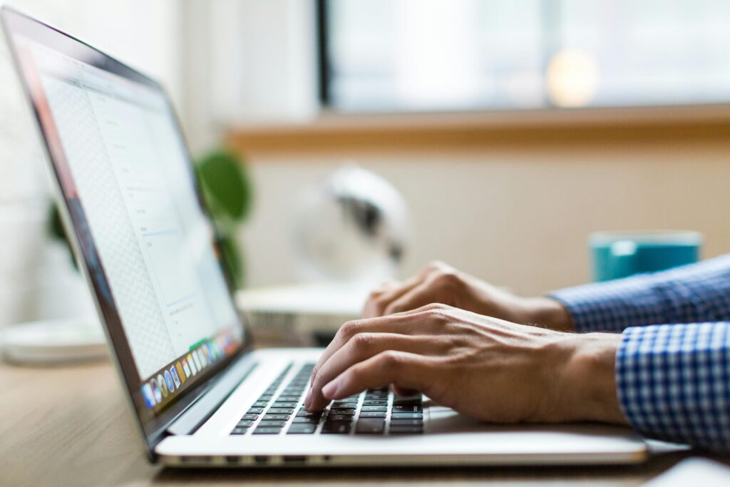 pexels-photo-374720-374720 Close-up of adult typing on laptop in bright, modern office.